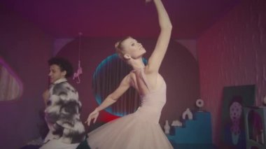 Neon ışıklandırmalı stüdyoda havalı iç tasarımı moda olan havalı hip hop dansçısıyla dans ederken çekilen zarif balerin pozunu büyüt.