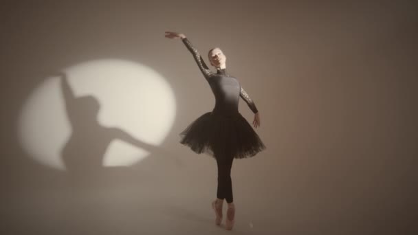 ブラックチュートゥで優雅なバレリーナのフルショット サイクルウォールでスタジオでスポットライトの下でポントで古典的なバレエを踊る — ストック動画
