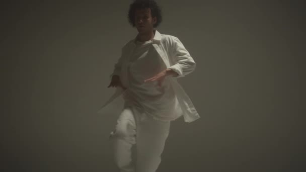 白いスーツで若い男性ダンサーのシュートダウンショットサイクルウォールでスタジオで裸足を踊る — ストック動画