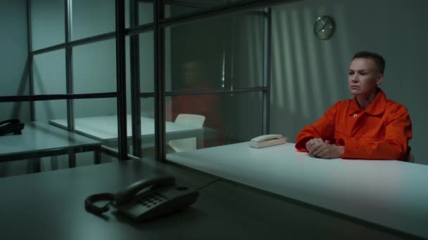 Заключенная Оранжевой Тюремной Форме Сидит Столом Стационарным Телефоном Стеклянной Стеной — стоковое видео