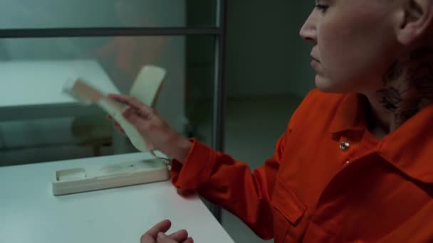 刑務所での訪問中に電話で話す首と短いヘアカットのタトゥーで女性受刑者 — ストック動画