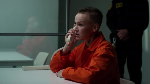 身穿橙色监狱制服的紧张女囚犯坐在会议室里 通过电话与来访者进行情绪化的交谈 — 图库视频影像