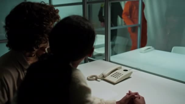 Afroamerikanische Häftlinge Gehen Besuchszimmer Sitzen Hinter Glaswand Und Telefonieren Mit — Stockvideo