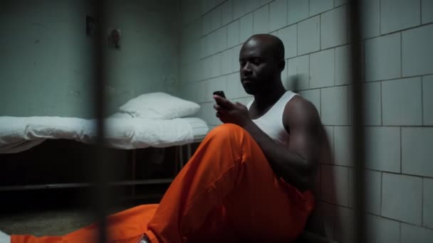 Blick Durch Gitter Afroamerikanischer Häftling Sitzt Gefängniszelle Auf Dem Boden — Stockvideo