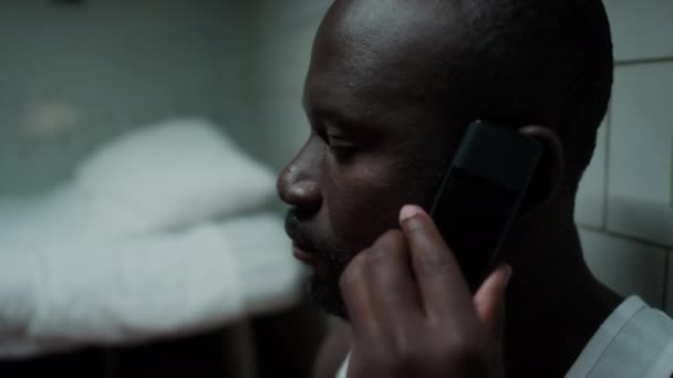 Ujęcie Czarnego Więźnia Siedzącego Celi Opierającego Się Ścianę Rozmawiającego Przez — Wideo stockowe
