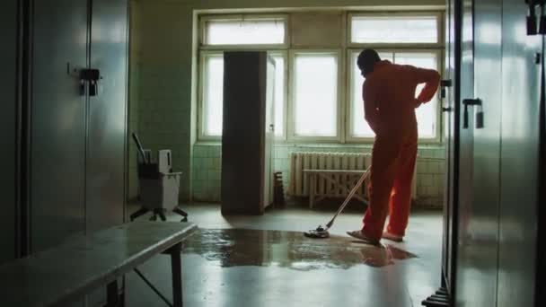 Całkowite Ujęcie Czarnego Więźnia Pomarańczowym Mundurze Myjącego Podłogę Podczas Sprzątania — Wideo stockowe