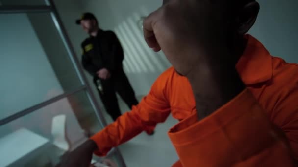 悲しいアフリカ系アメリカ人の収容者が目をこすり 訪問室で電話で感情的な話をする様子を撮影 — ストック動画