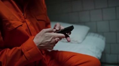 Kadın mahkumun karanlık bir hücrede yatarken, numarayı çevirirken ve heyecanla cep telefonuyla konuşurken görüntüsünü kaldır.