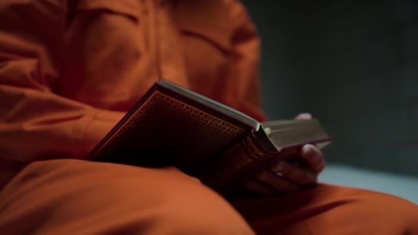 Detailní Záběr Rukou Neznámého Vězně Oranžové Vězeňské Uniformě Čtení Bible — Stock video