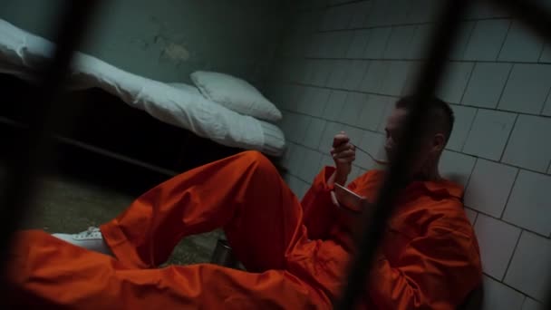 Hapishane Hücresinde Yerde Oturan Çelik Kaseden Yemek Yiyen Turuncu Tulumlu — Stok video