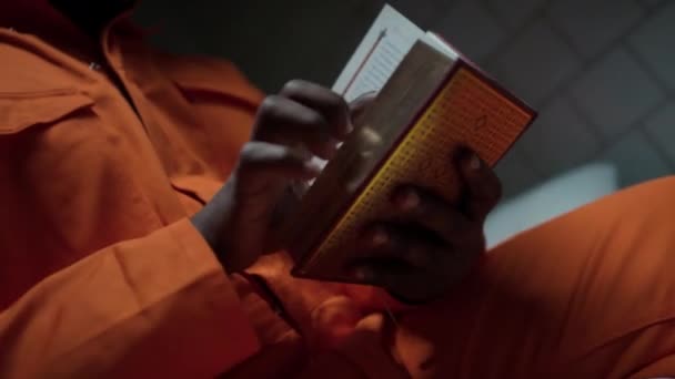 Nahaufnahme Eines Verzweifelten Schwarzen Häftlings Der Der Zelle Bibel Liest — Stockvideo
