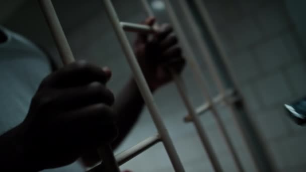 Zbliżenie Afroamerykanina Stojącego Kratkami Więziennej Celi Odbierającego Telefon Skorumpowanego Strażnika — Wideo stockowe