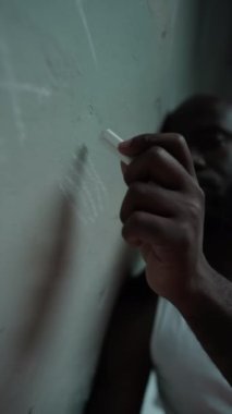 Hapishanede günleri hesaplarken duvara çizim yapan siyah mahkumun dikey yakın görüntüsü