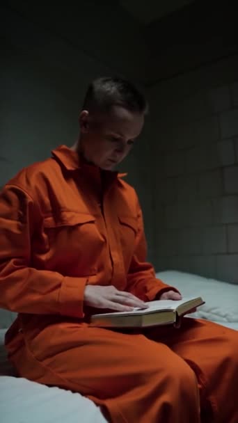 Вертикальный Снимок Женщины Заключенной Сидящей Кровати Тюремной Камере Читающей Священную — стоковое видео