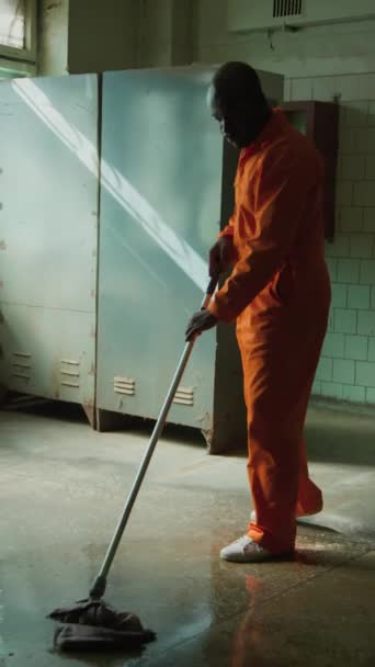 Vertikální Plný Záběr Afroamerického Vězně Oranžové Vězeňské Kombinéze Drhnutí Podlahy — Stock video