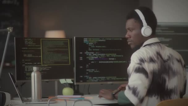Νεαρός Αφροαμερικανός Προγραμματιστής Ακουστικά Πόσιμο Νερό Και Πληκτρολογώντας Κώδικα Υπολογιστή — Αρχείο Βίντεο