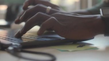 Ofisteki iş yerinde dizüstü bilgisayarda yazan tanınmayan bir adamın ellerine yakından bak.