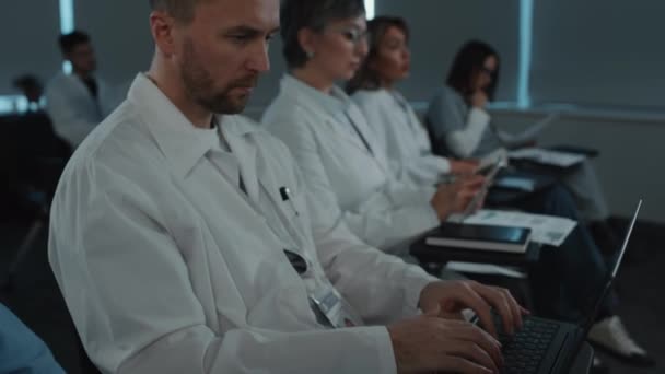 Beyaz Önlüklü Erkek Doktor Meslektaşlarıyla Oturuyor Hoparlörleri Dinliyor Tıp Konferansında — Stok video