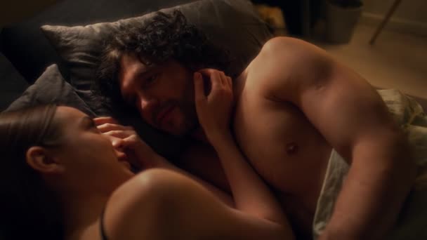 从上面看这对年轻夫妇躺在床上 躺在毯子下 在浪漫的夜晚拥抱和交谈 — 图库视频影像