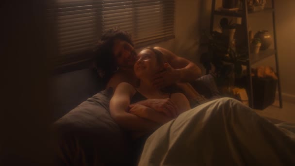 若い愛する男と女性は寝室で抱きしめ 自宅で夜にチャットして微笑む — ストック動画