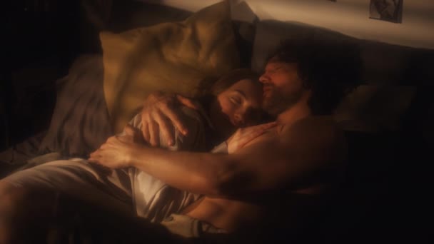 ベッドでロマンチックな夜を過ごしながらハッピーガールフレンドを抱きしめキスするシャツレス男性のハイアングルショット — ストック動画