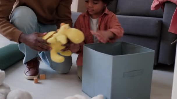 Africký Americký Otec Pomáhá Malému Synovi Balením Plyšových Hraček Krabici — Stock video