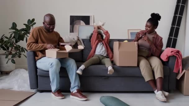 Afroamerykanie Rodzice Synek Siedzą Kanapie Salonie Pakują Rzeczy Pudeł Przygotowując — Wideo stockowe