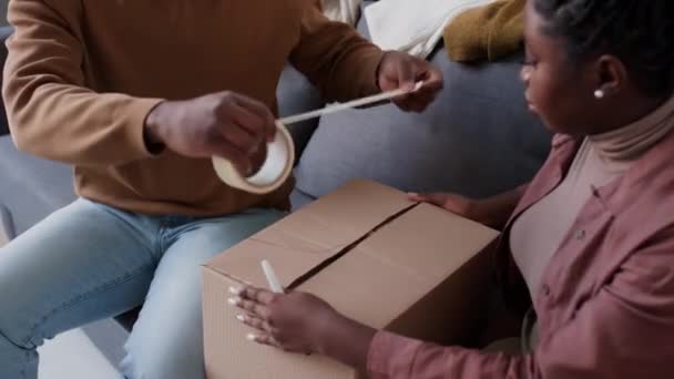 Afroamerykańska Rodzina Uszczelniająca Kartonowe Pudełko Taśmą Samoprzylepną Podczas Pakowania Rzeczy — Wideo stockowe