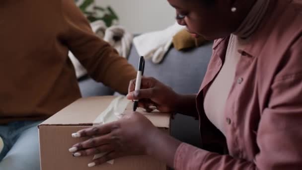 Afrikansk Amerikansk Kvinna Skriver Leksaker Med Penna Förpackad Kartong Medan — Stockvideo