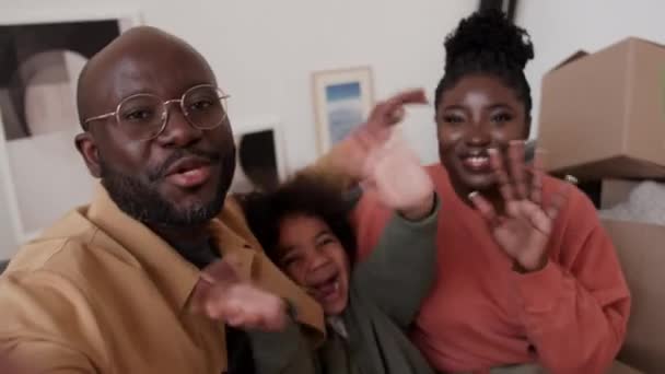 快乐的非洲裔美国人父母和小孩看着摄像机 通过网上视频挥手聊天 搬进新家后带着打开的盒子坐在沙发上的Pov视频 — 图库视频影像