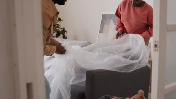 Casal Família Preta Removendo Tampa Plástico Sofá Depois Mudar Casa — Vídeo de Stock