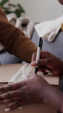 Afro-Amerikalı bir kadının, yeni eve taşınmaya hazırlanırken keçeli kalemle imzalı imzasını dikey yakın plan çekimleri.