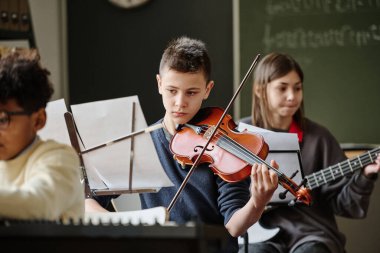 Okul orkestrasıyla çalışırken müzik okuyan ve keman çalan oğlanın seçici odak noktası