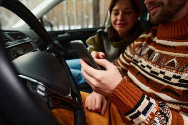 Modern Kafkasyalı çiftin kış günü akıllı telefondan harita okurken seçmeli odak noktası.