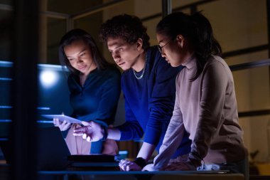 Bir grup modern bilişim uzmanı akşam geç saatlerde yeni yazılımlar geliştiriyor ve test ediyorlar.