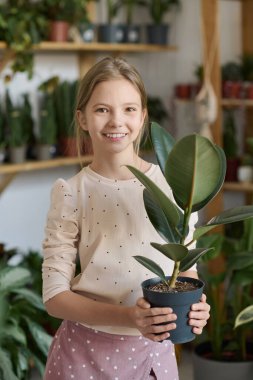 Kameraya gülümseyen beyaz bir kızın dikey orta boy portresi.