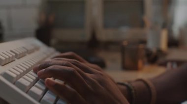 Afrika kökenli Amerikalı hackerın fütüristik kulaklıklarıyla bilgisayar klavyesinde yazarken ve kıyamet sonrası sığınakta çelik bardaktan çay içerken yakın çekim görüntüsü.