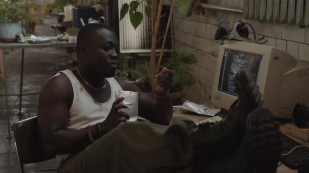 Молодий Афроамериканський Чоловік Сидить Ногами Столі Їсть Консервовану Їжу Фольги — стокове відео