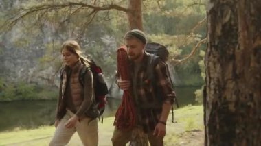 Genç erkek ve dişi gezginler yaz yürüyüşü sırasında ormanda yürürler.