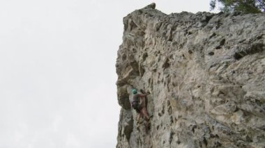 Yaz günü doğada ekstrem sporlar yaparken dik kayalara tırmanan adamın görüntüsü.