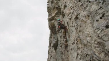 Profesyonel dağcının kask takıp kayadan kayadan kayarak indiği geniş bir çekim yaz günü.