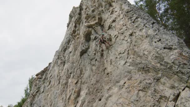 Широкий Наклон Снимок Альпиниста Спускающегося Крутой Скалы Пока Девушка Стоит — стоковое видео