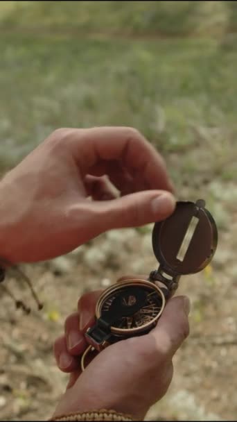 男子旅行家打开指南针并在夏季远足时用它在大自然中导航的双手垂直近照 — 图库视频影像