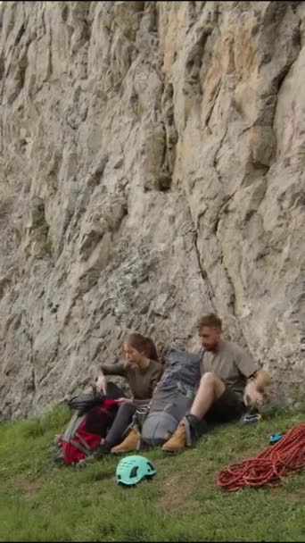 一对登山伙伴坐在岩石底部 从背包上取下登山装备的垂直镜头 — 图库视频影像