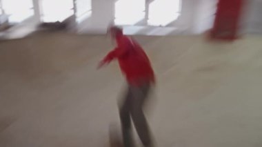 Hareket bulanıklığı olan el kamerasıyla kayak yapan genç bir adamın kapalı alan kaykay pistinde aşağı yukarı kayışı efekti.