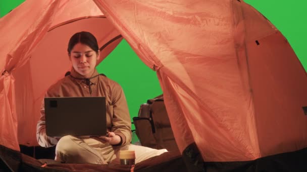 女孩在绿色色彩艳丽的帐篷里用笔记本电脑和镜头拍照的肖像 — 图库视频影像