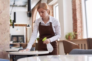 Restoranda önlük giyip deterjan kullanırken orta boy beyaz garson pozu.