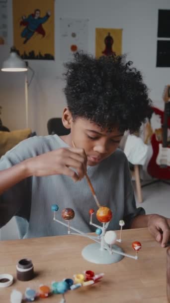 Pionowe Ujęcie Małego Czarnego Chłopca Używającego Gwaszu Podczas Malowania Planet — Wideo stockowe