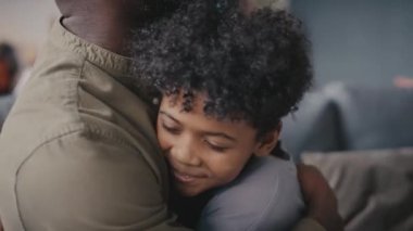 Afrikalı Amerikalı babayı sevmek, gülümseyen küçük oğlunu kucaklamak ve evde onunla konuşmak.