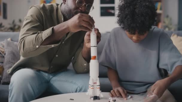 Наклонный Снимок Афроамериканского Отца Маленького Сына Вместе Строящих Ракетную Модель — стоковое видео